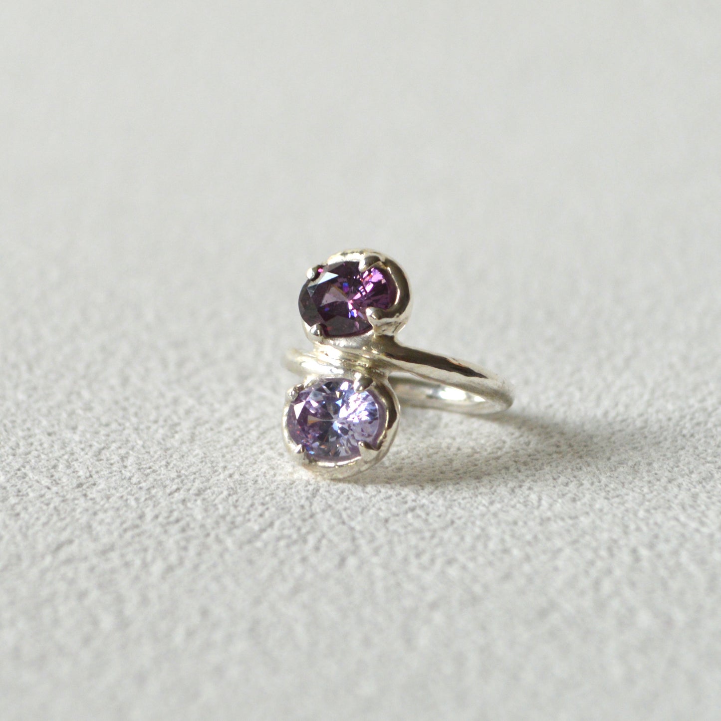 Silver ring with purple gemstones on a light gray background