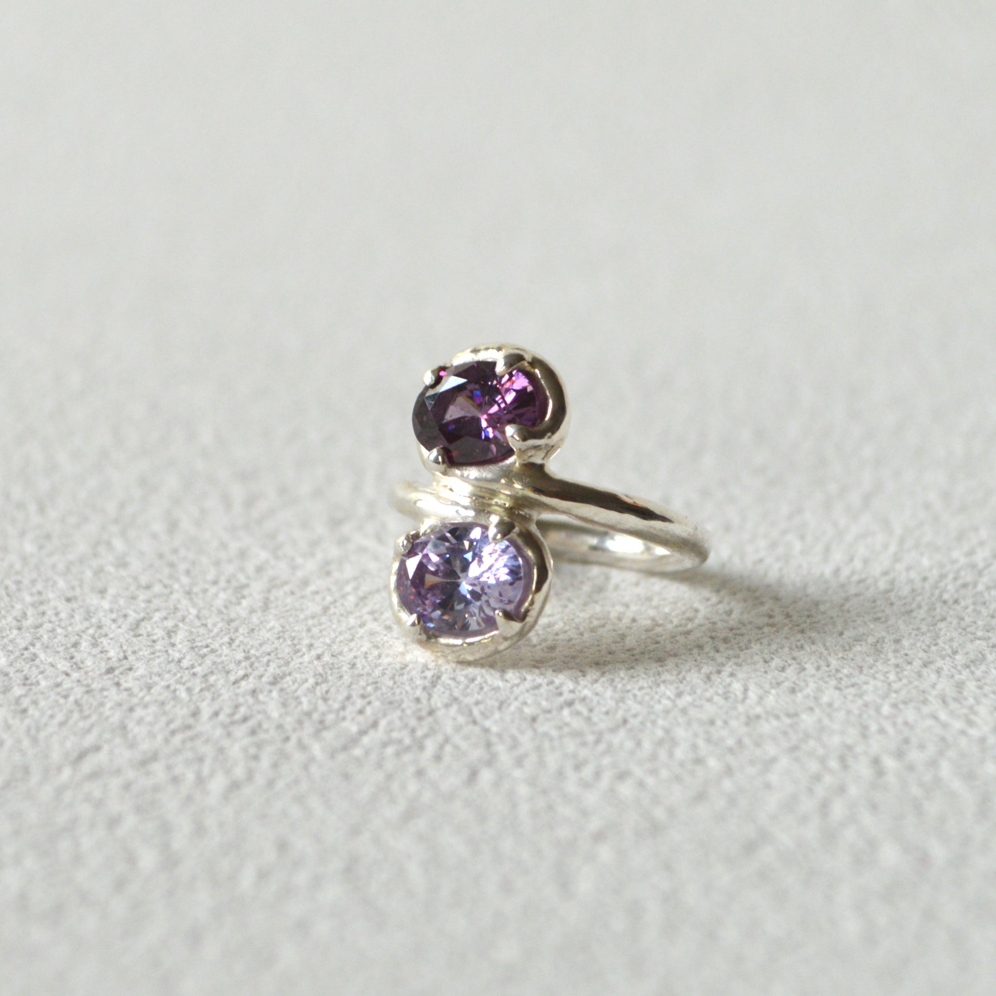 Silver ring with purple gemstones on a light gray background