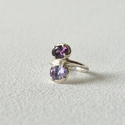 Silver ring with purple gemstones on a light gray background