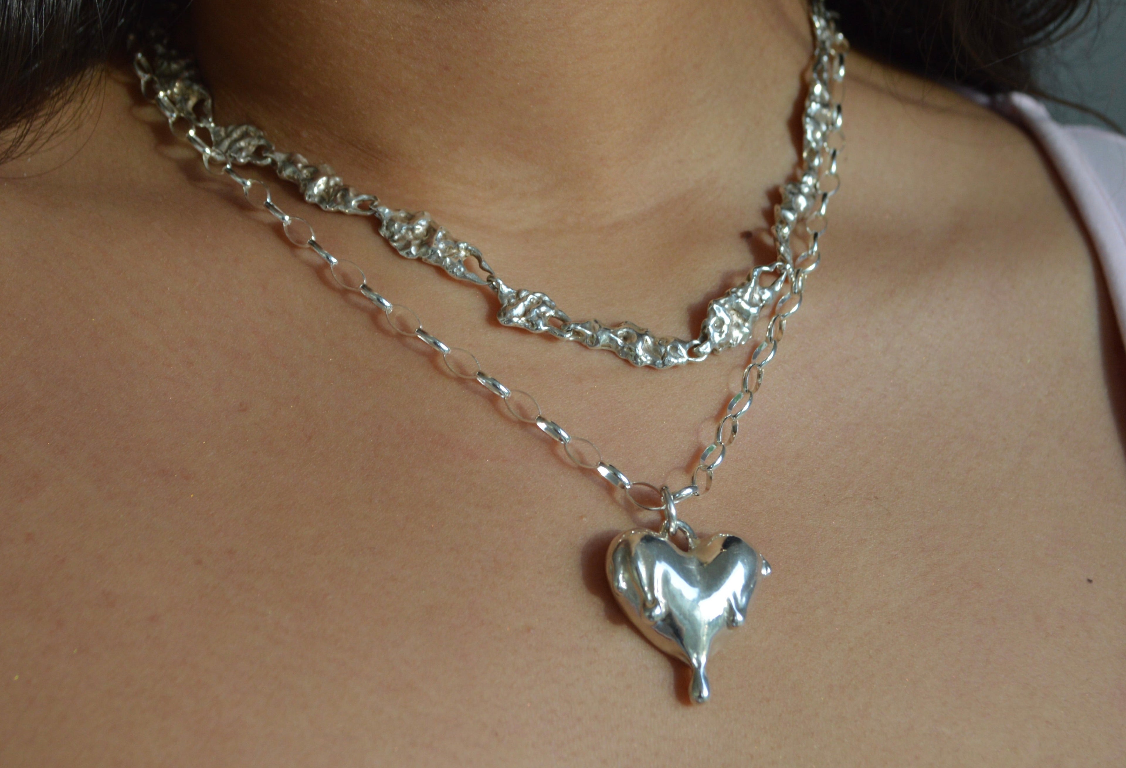 Silver heart-shaped pendant necklace on a person's neck